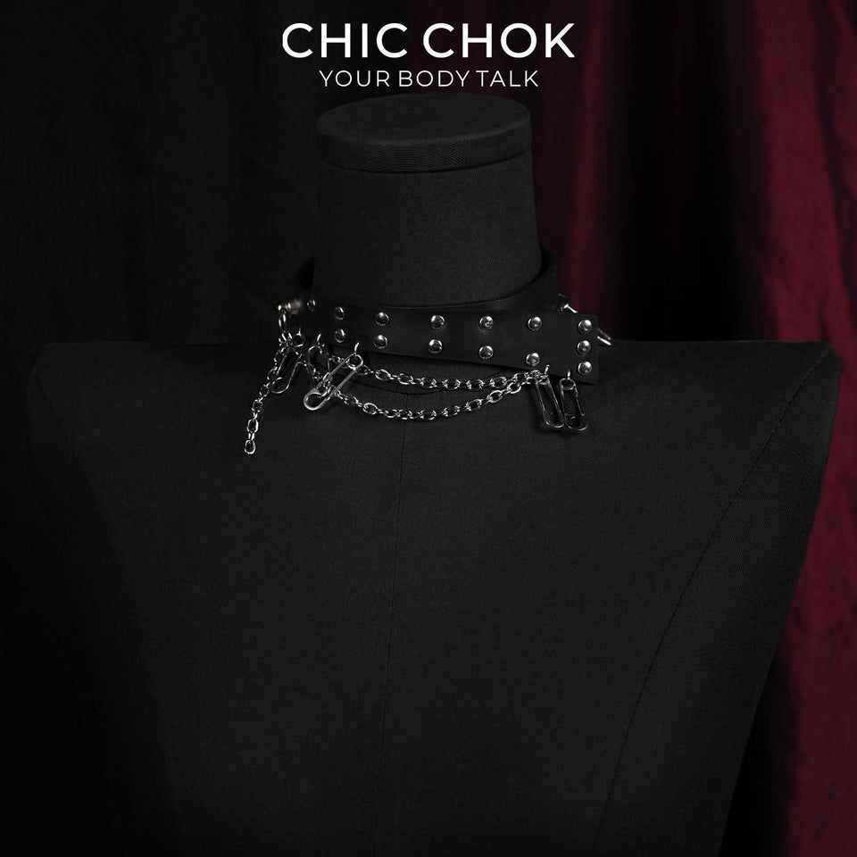 Black strap choker with rivets, safety pins, and hanging chains on a necklace display