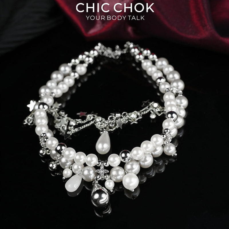 Fractured Cloud necklace with white beads, silver-colored chains and star-shaped charms on a dark background